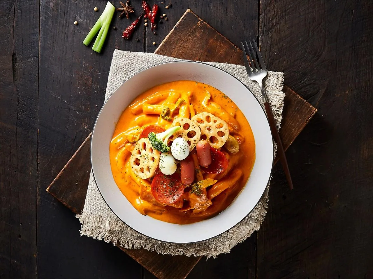 흰 볼에 담긴 응큼 로제떡볶이 — 연근과 소시지, 브로콜리를 올린 크리미한 로제 소스