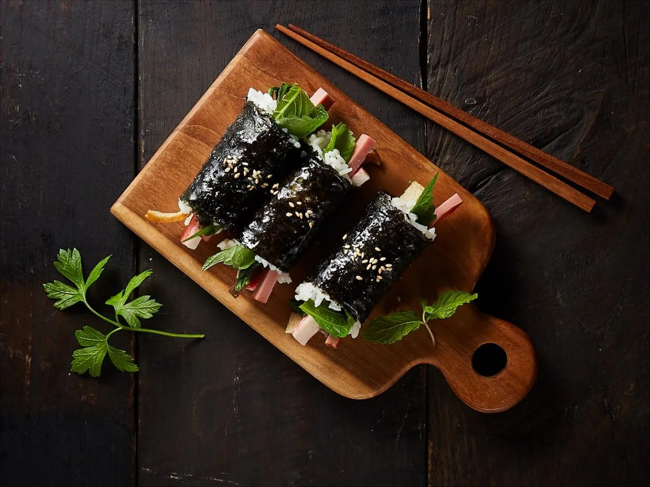 나무 도마 위에 나란히 놓인 꼬마김밥과 나무젓가락